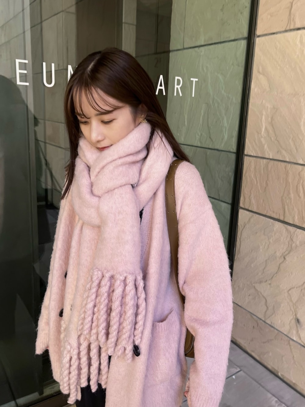 イエロー系のショルダーバッグ、ピンク系のカーディガン/ボレロ、ブラック系のスニーカーを着用したレディースの冬コーディネートの5枚目の写真