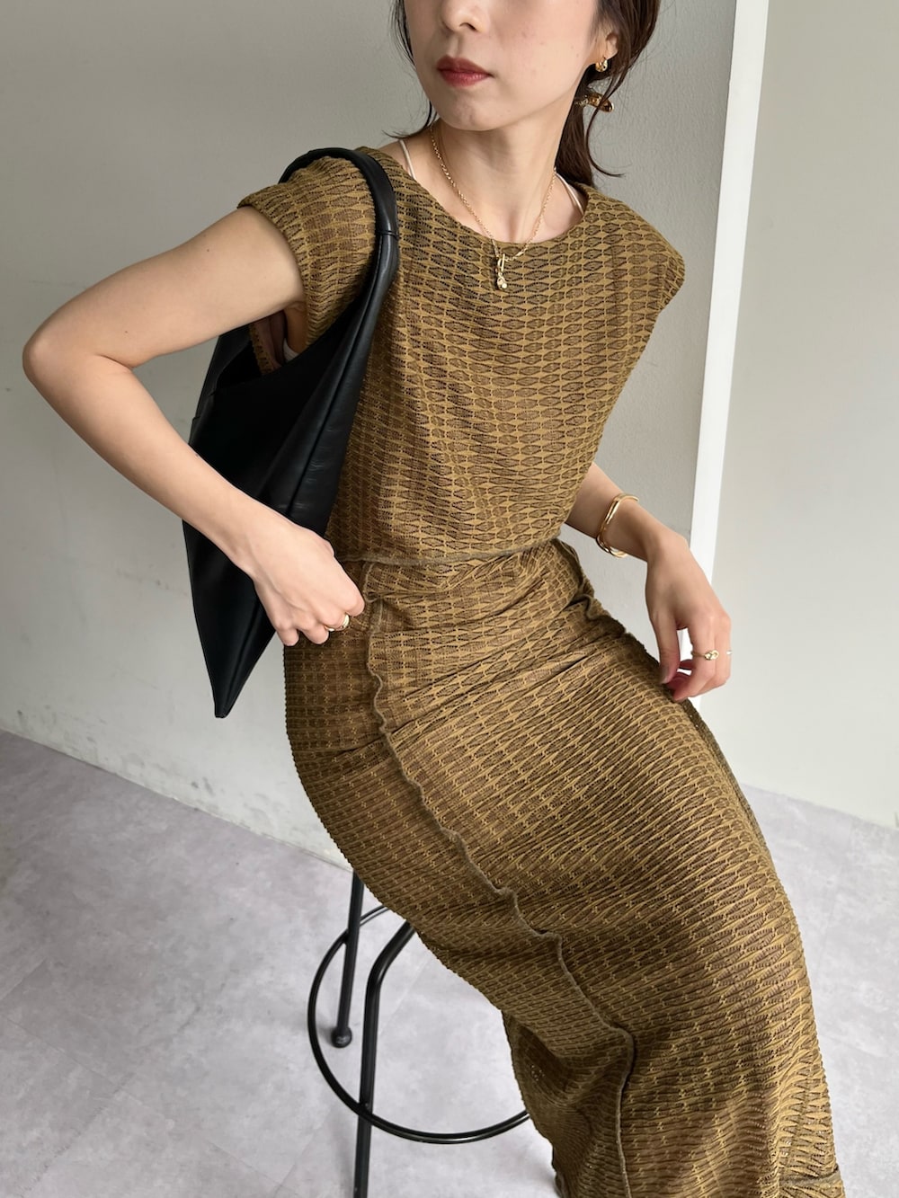 ベージュ系のワンピース、ブラック系のバッグ、ブラック系のサンダルを着用したレディースの春コーディネートの2枚目の写真