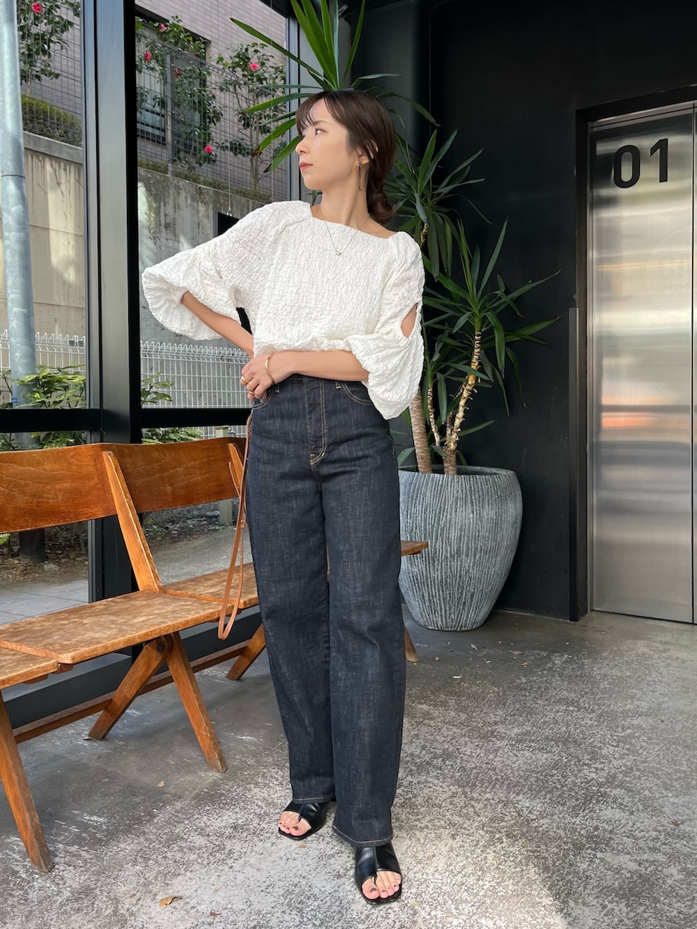 ブラック系のサンダル、ホワイト系のシャツ/ブラウス、ブルー系のデニムパンツを着用したレディースの春コーディネートの2枚目の写真