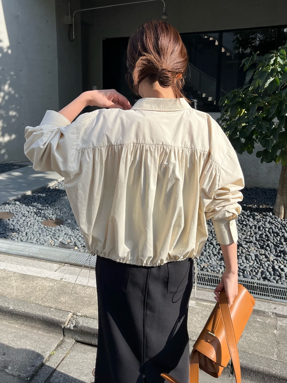 ブラック系のスカート、ベージュ系のショルダーバッグ、ブラック系のブーツを着用したレディースの春コーディネートの4枚目の写真