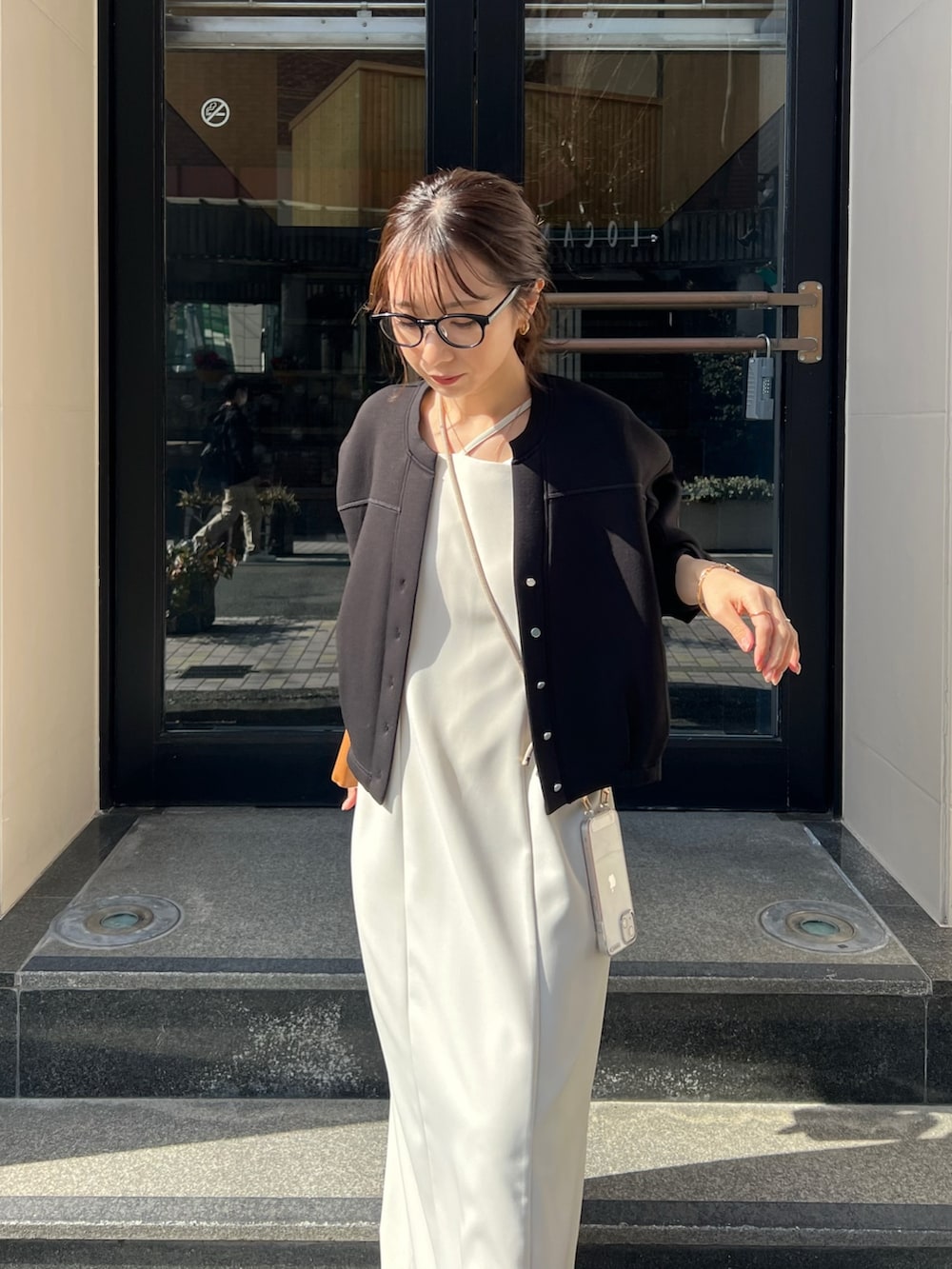 ブラック系のワンピース、ブラック系のカーディガン/ボレロ、ホワイト系のサンダルを着用したレディースの冬コーディネートの3枚目の写真