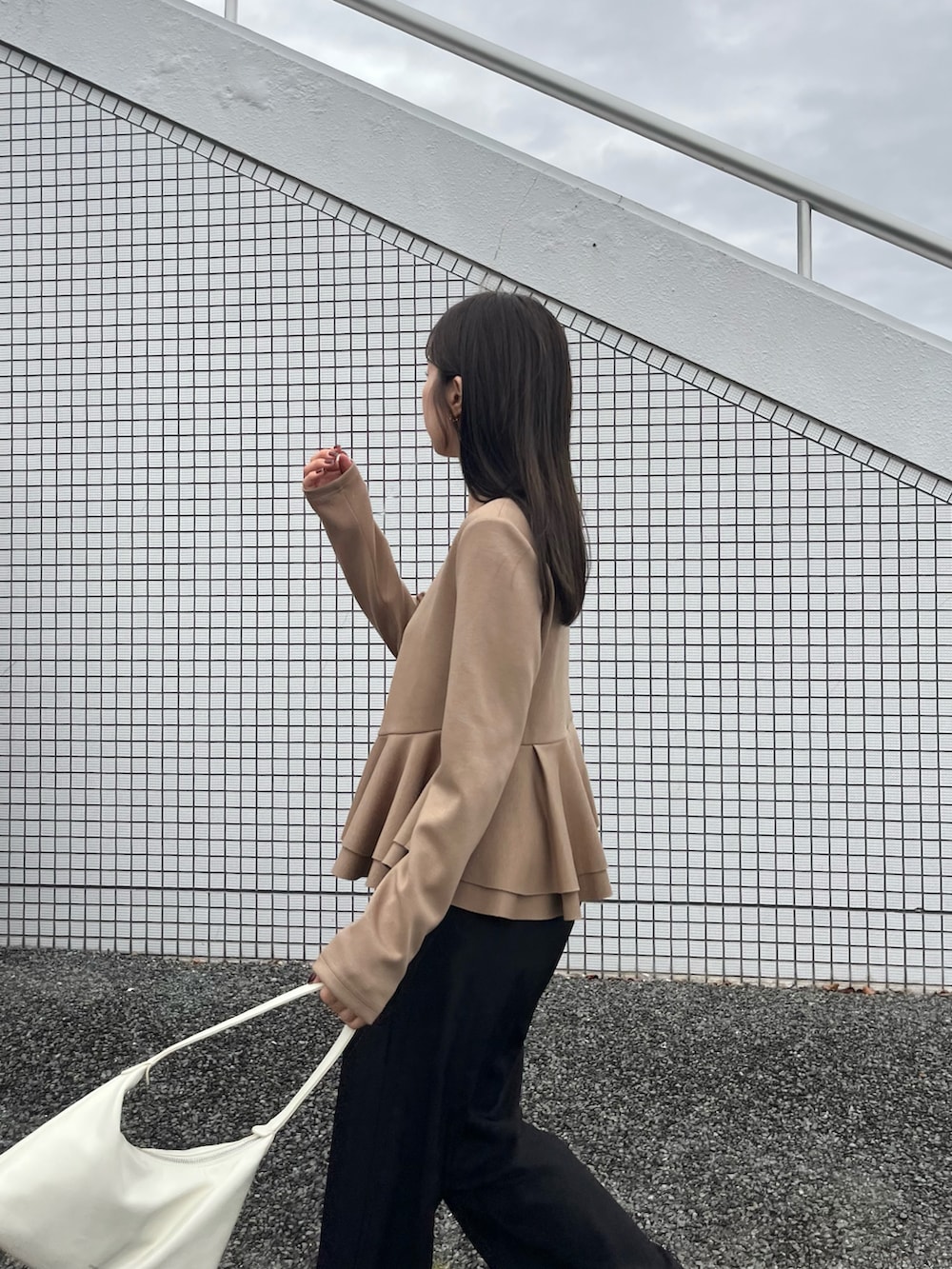 ベージュ系のTシャツ/カットソー、ブラック系のスラックス、ブラック系のローファーを着用したレディースの冬コーディネートの3枚目の写真