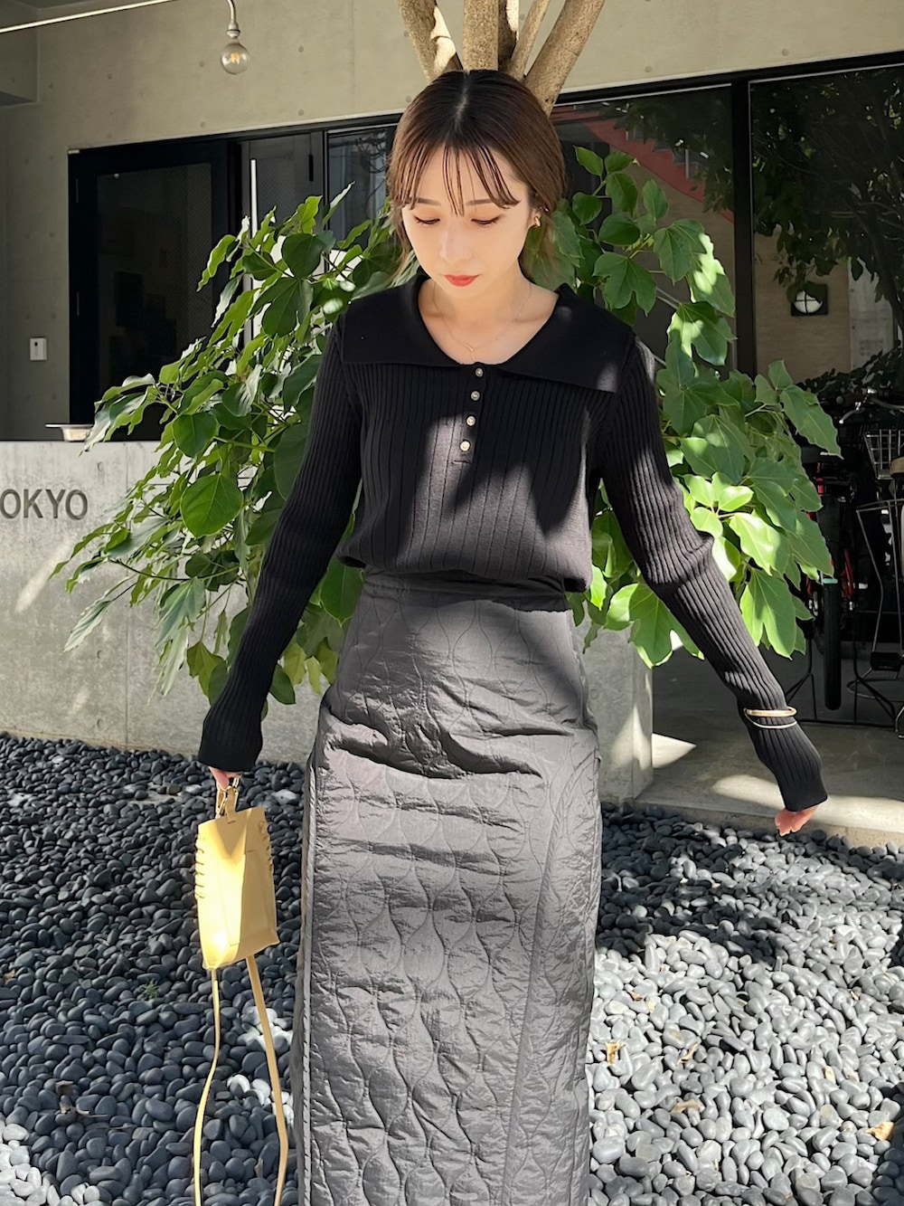 ブラック系のニット/セーター、ブラック系のスカート、イエロー系のハンドバッグを着用したレディースの秋コーディネートの5枚目の写真