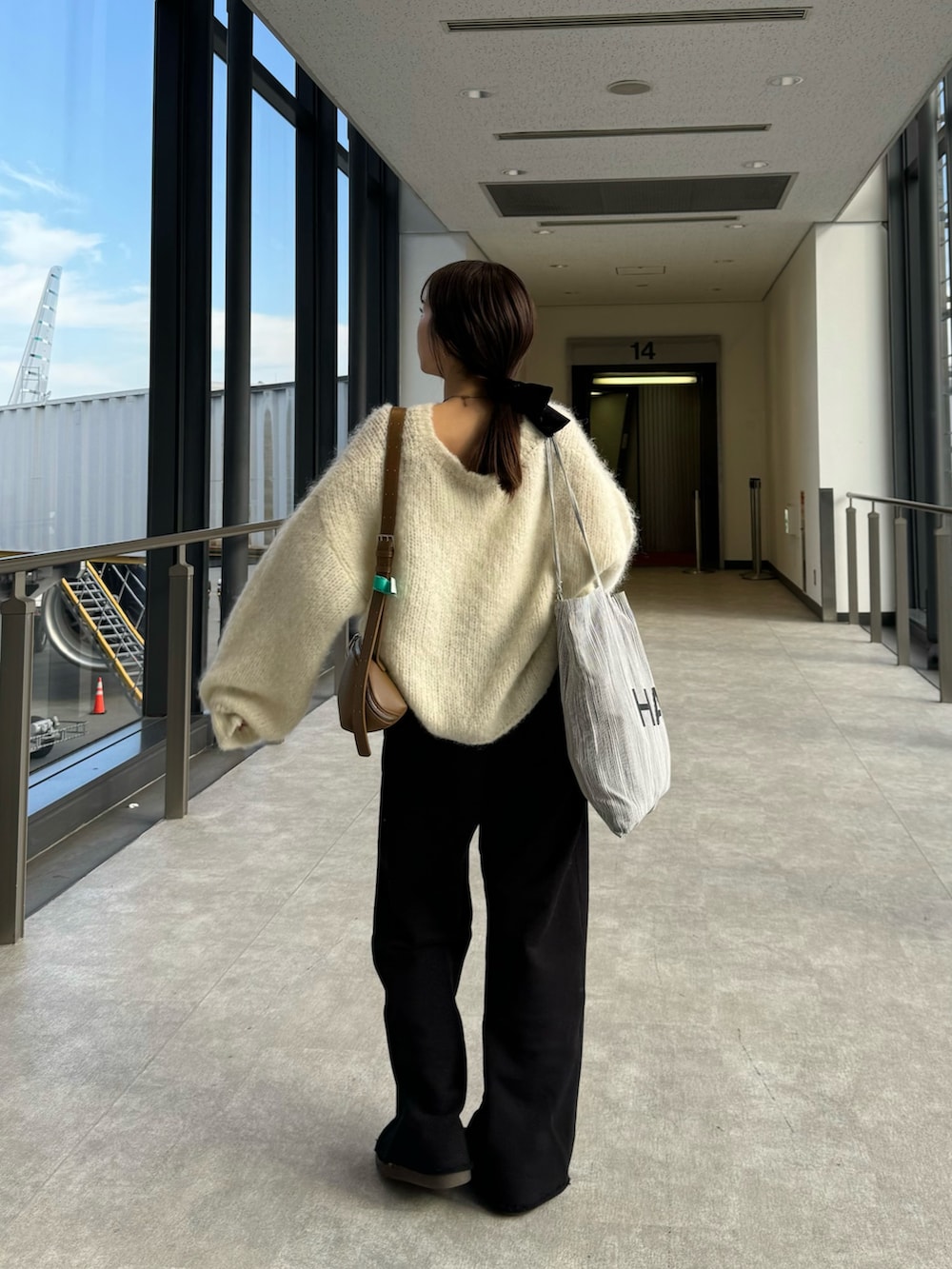 ブラック系のスウェットパンツ、ホワイト系のニット/セーター、ブラック系のスニーカーを着用したレディースの秋コーディネートの5枚目の写真