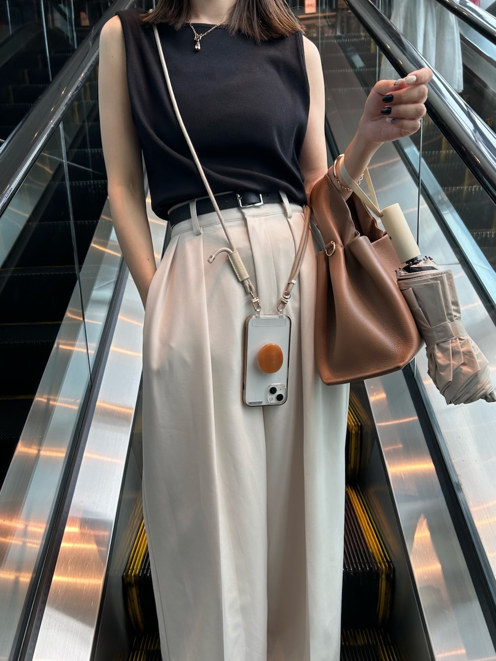 ブラック系のトップス、ブラウン系のバッグ、ホワイト系のその他パンツを着用したレディースの夏コーディネートの5枚目の写真