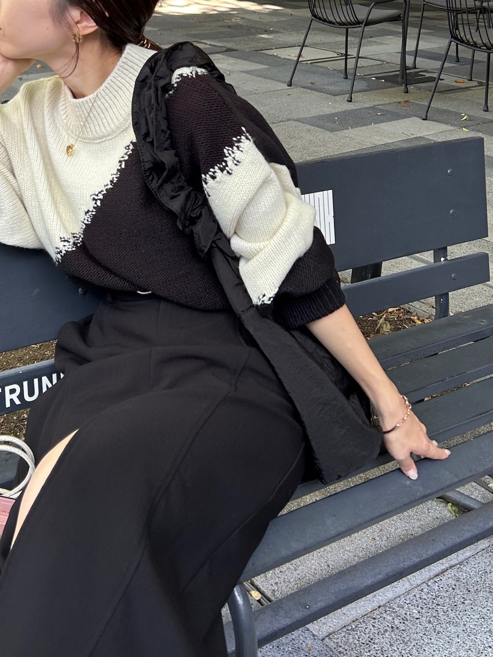 ブラック系のスカート、ホワイト系のニット/セーター、ブラック系のショルダーバッグを着用したレディースの秋コーディネートの4枚目の写真