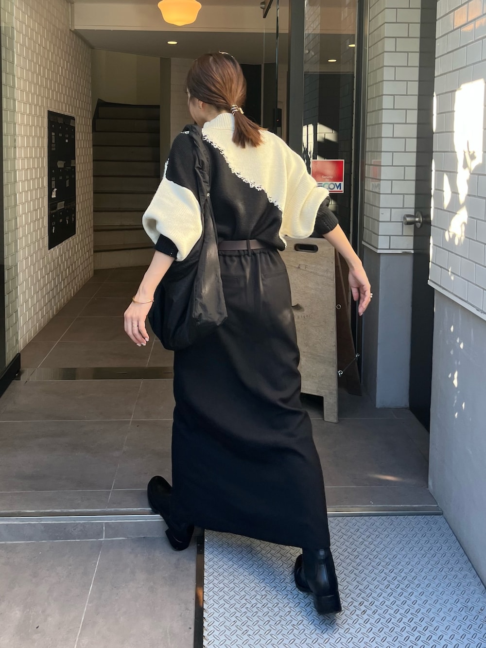 ブラック系のスカート、ホワイト系のニット/セーター、ブラック系のショルダーバッグを着用したレディースの秋コーディネートの2枚目の写真