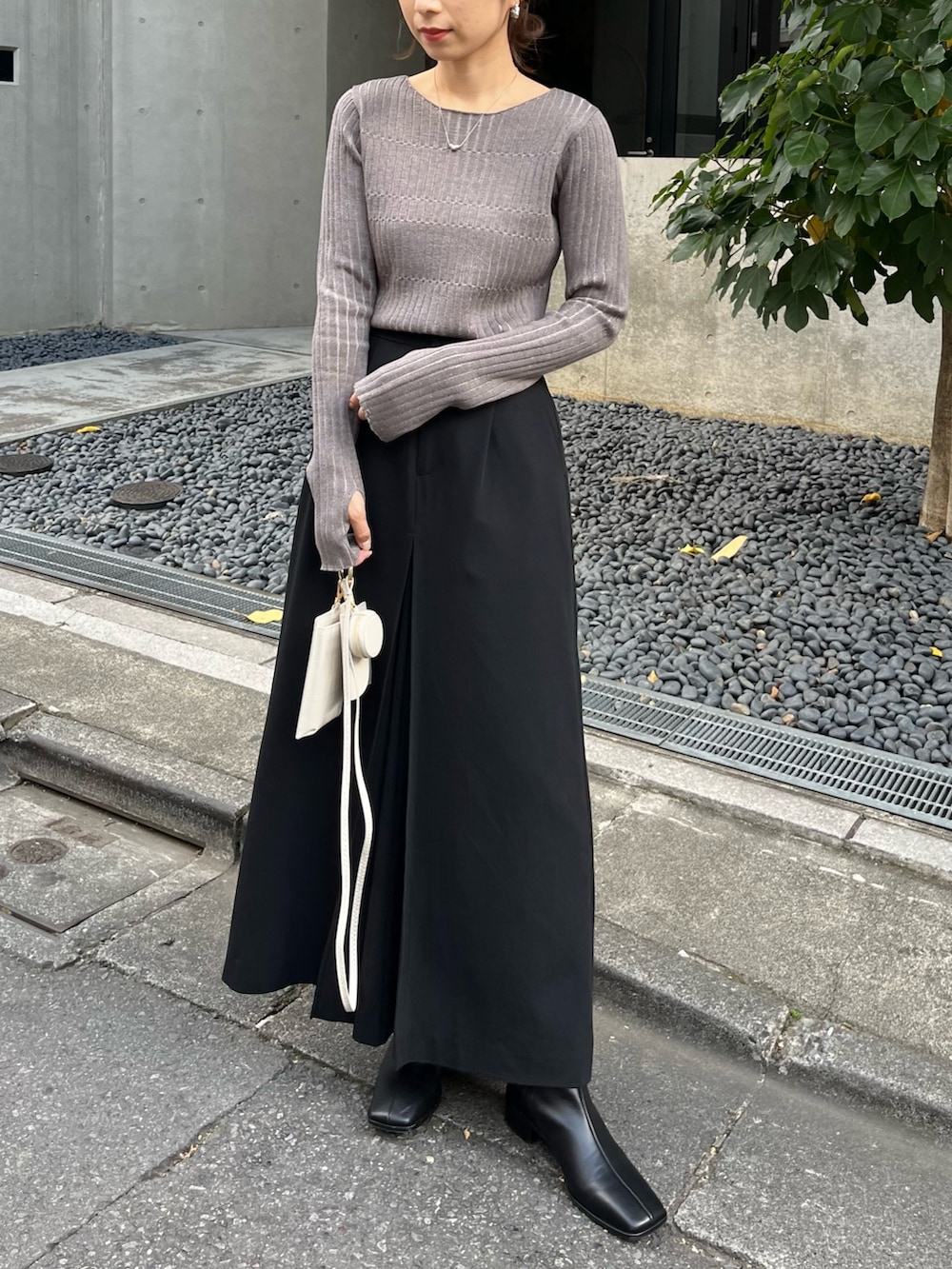 グレー系のニット/セーター、ブラック系のスカート、ブラック系のトートバッグを着用したレディースの秋コーディネートの3枚目の写真