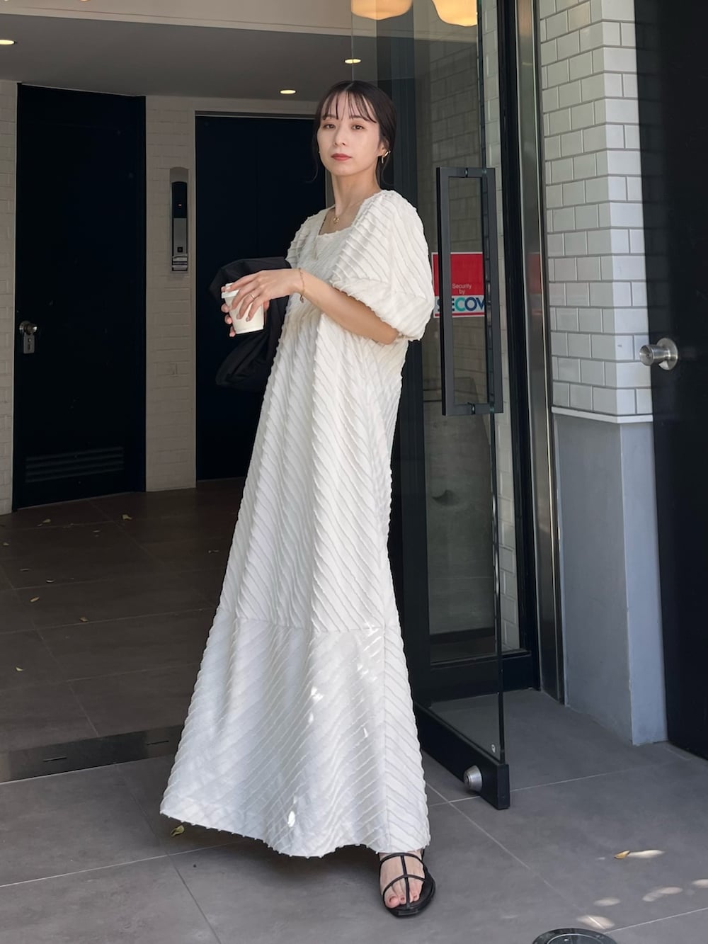 ホワイト系のワンピース、ブラック系のショルダーバッグ、ブラック系のその他シューズを着用したレディースの春コーディネートの5枚目の写真