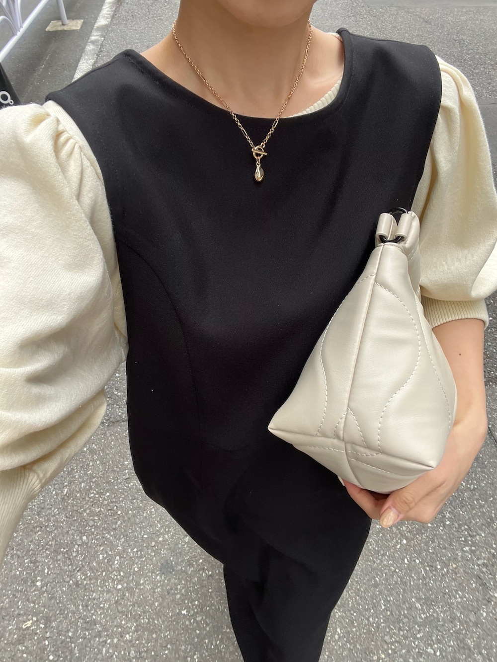 ブラック系のジャンパースカート、ホワイト系のニット/セーター、イエロー系のバッグを着用したレディースの春コーディネートの6枚目の写真