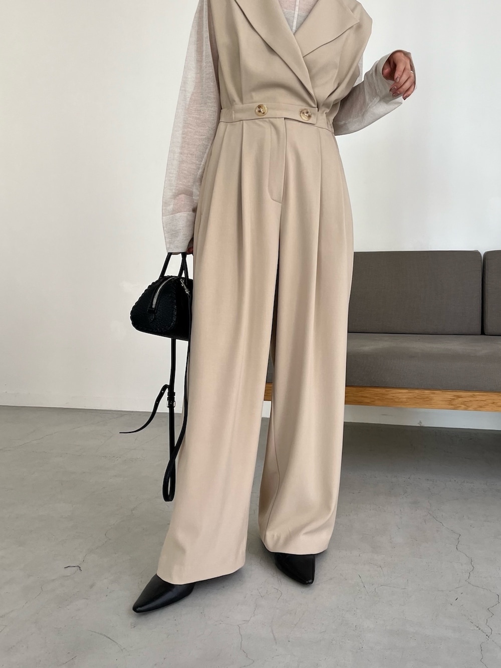 ブラック系のパンプス、ホワイト系のニット/セーター、ベージュ系のつなぎ/オールインワンを着用したレディースの冬コーディネートの6枚目の写真