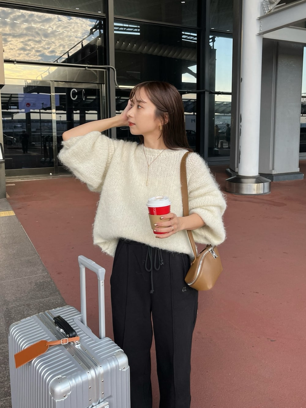 ブラック系のスウェットパンツ、ホワイト系のニット/セーター、ブラック系のスニーカーを着用したレディースの秋コーディネートの2枚目の写真