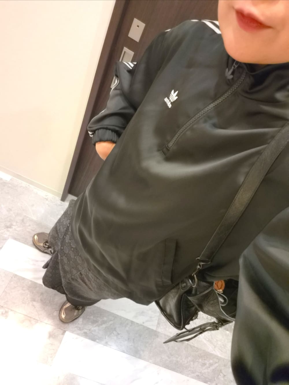ブラック系のスカート、ブラック系のジャージ、ブラック系のショルダーバッグを着用したレディースの秋コーディネートの4枚目の写真