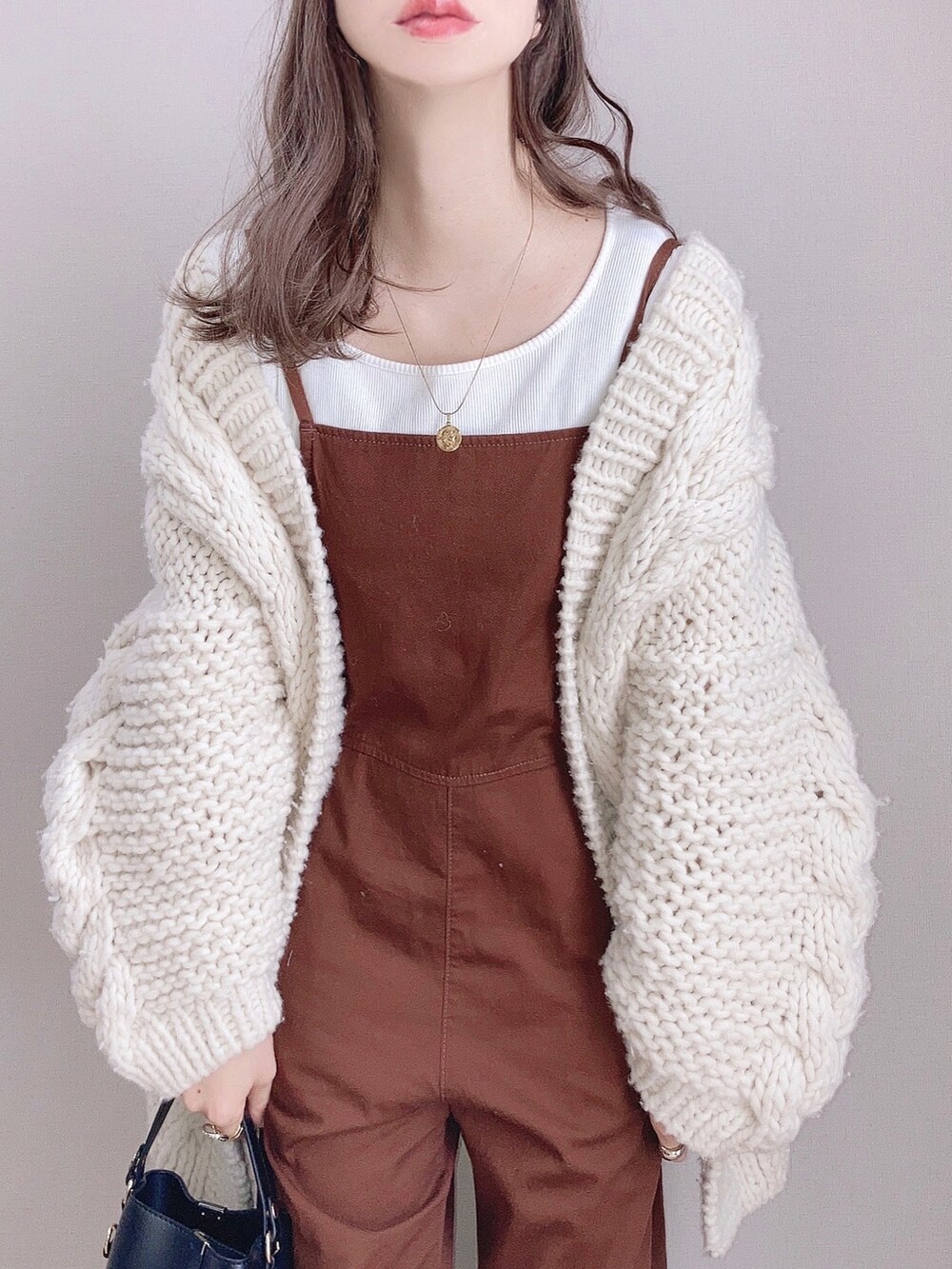 ホワイト系のカーディガン/ボレロ、ホワイト系のTシャツ/カットソー、ブラック系のショルダーバッグを着用したレディースの冬コーディネートの2枚目の写真