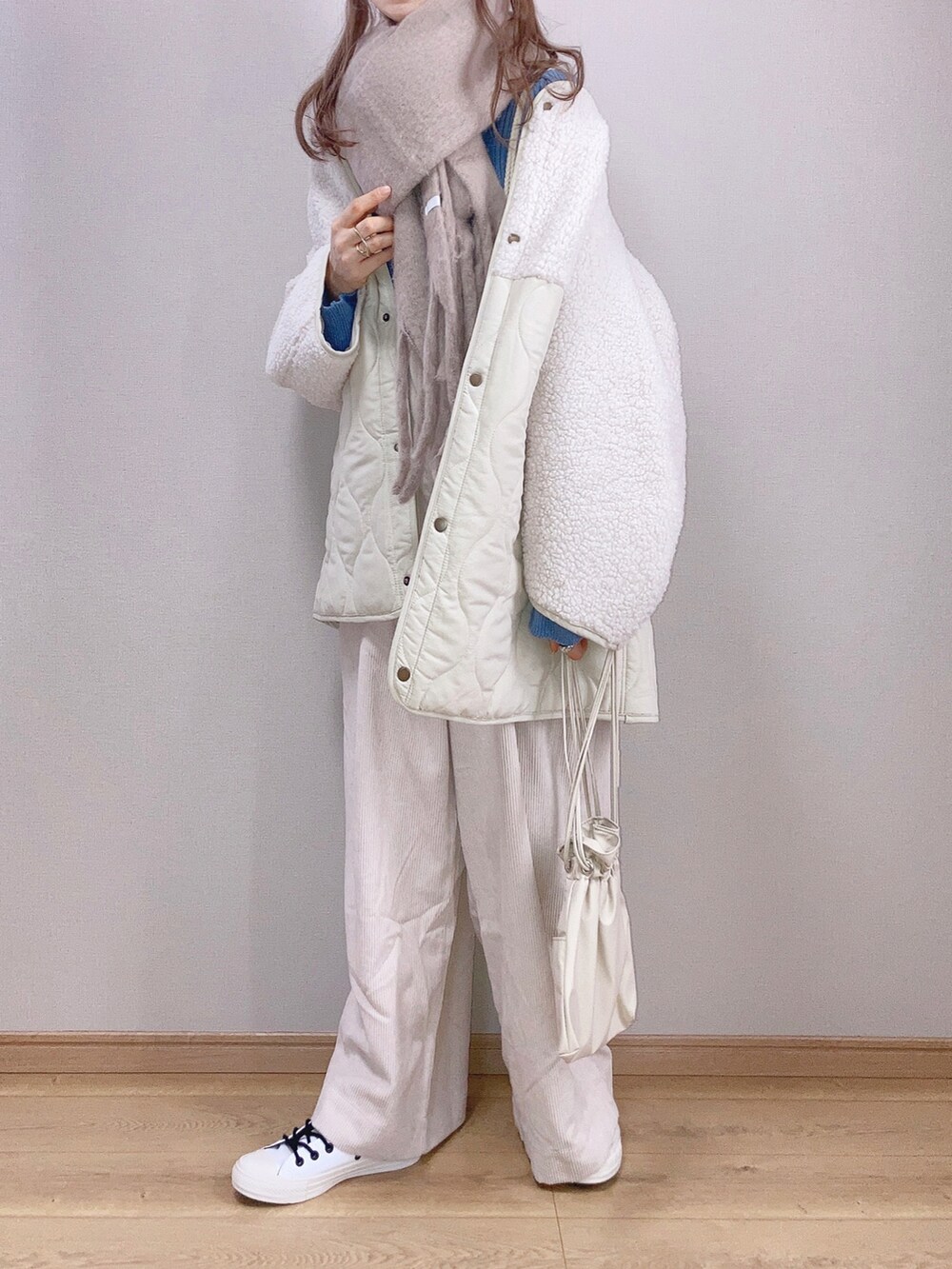 ホワイト系のブルゾン、ブルー系のニット/セーター、ホワイト系のサロペット/オーバーオールを着用したレディースの冬コーディネートの2枚目の写真