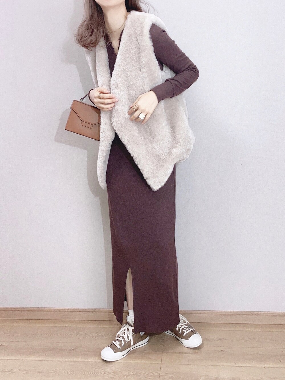 グレー系のベスト、ブラウン系のワンピース、ブラウン系のショルダーバッグを着用したレディースの冬コーディネートの3枚目の写真