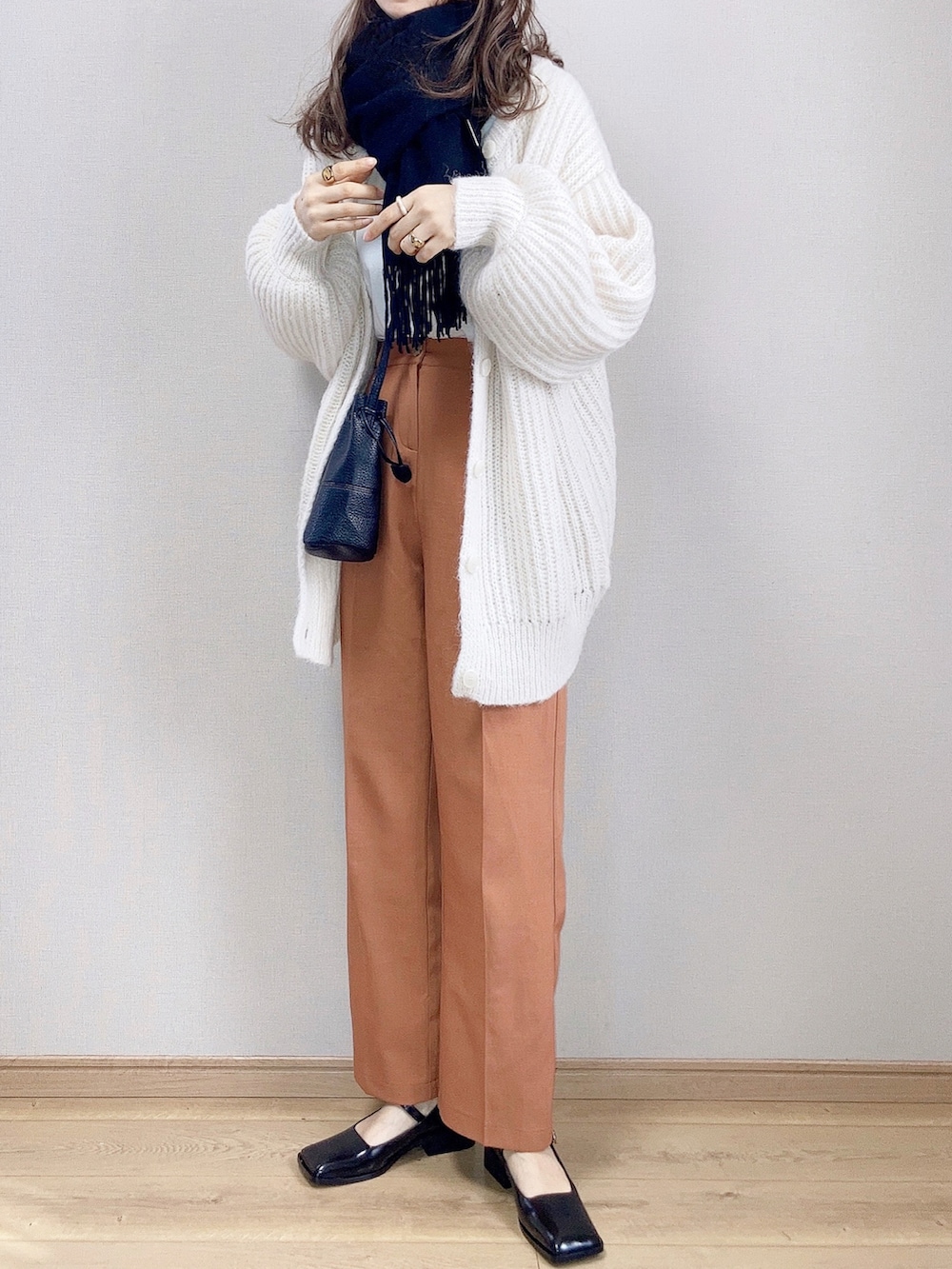 ホワイト系のカーディガン/ボレロ、ブラック系のパンプス、ブラック系のショルダーバッグを着用したレディースの冬コーディネートの2枚目の写真