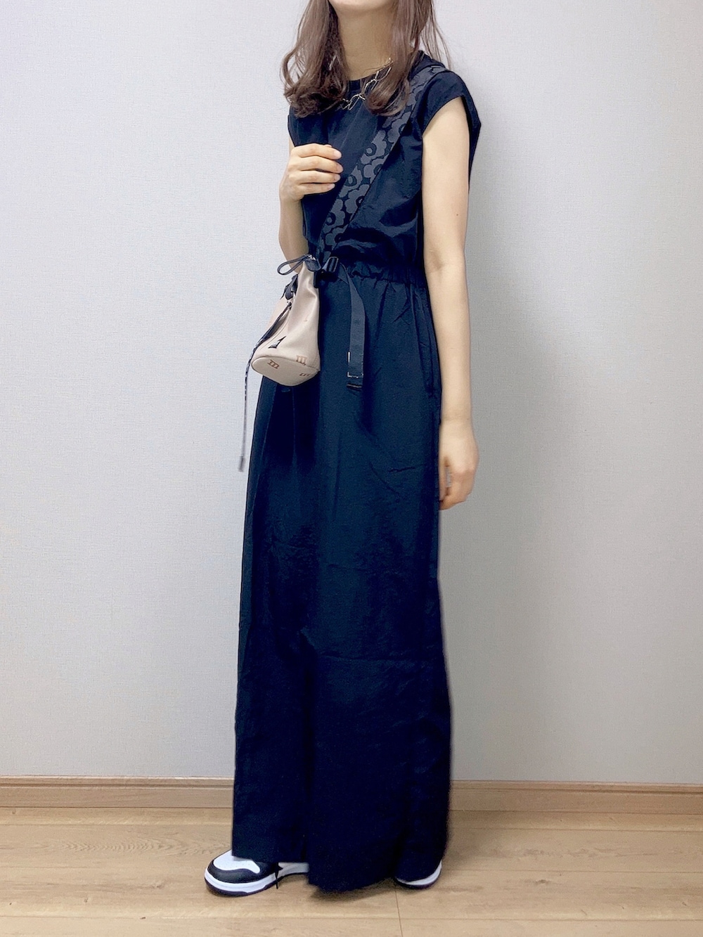 ブラック系のワンピース、ベージュ系のショルダーバッグ、ホワイト系のスニーカーを着用したレディースの夏コーディネートの2枚目の写真