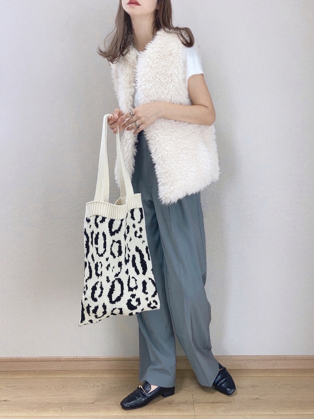 グレー系のスラックス、ホワイト系のベスト、ホワイト系のTシャツ/カットソーを着用したレディースの秋コーディネートの2枚目の写真