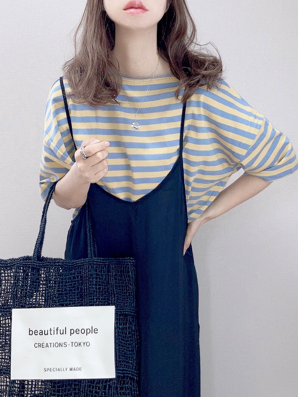 イエロー系のTシャツ/カットソー、ブラック系のワンピース、ブラック系のトートバッグを着用したレディースの春コーディネートの2枚目の写真