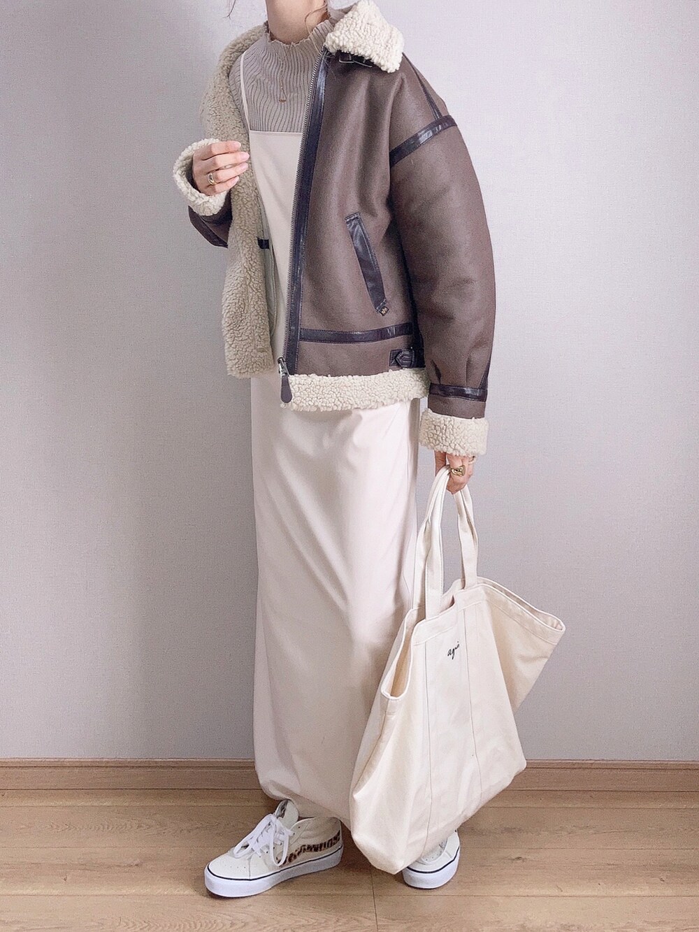 ブラウン系のムートンコート、ブラウン系のニット/セーター、ホワイト系のワンピースを着用したレディースの秋コーディネートの3枚目の写真