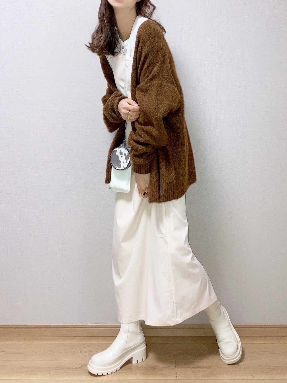 ベージュ系のブーツ、ホワイト系のワンピース、ホワイト系のショルダーバッグを着用したレディースの秋コーディネートの2枚目の写真