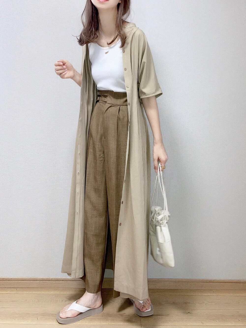 ベージュ系のワンピース、ホワイト系のタンクトップ、ブラウン系のスラックスを着用したレディースの夏コーディネートの2枚目の写真