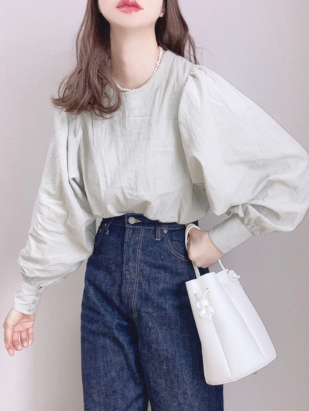 ブルー系のデニムパンツ、ホワイト系のバッグ、ブラウン系のパンプスを着用したレディースの冬コーディネートの2枚目の写真