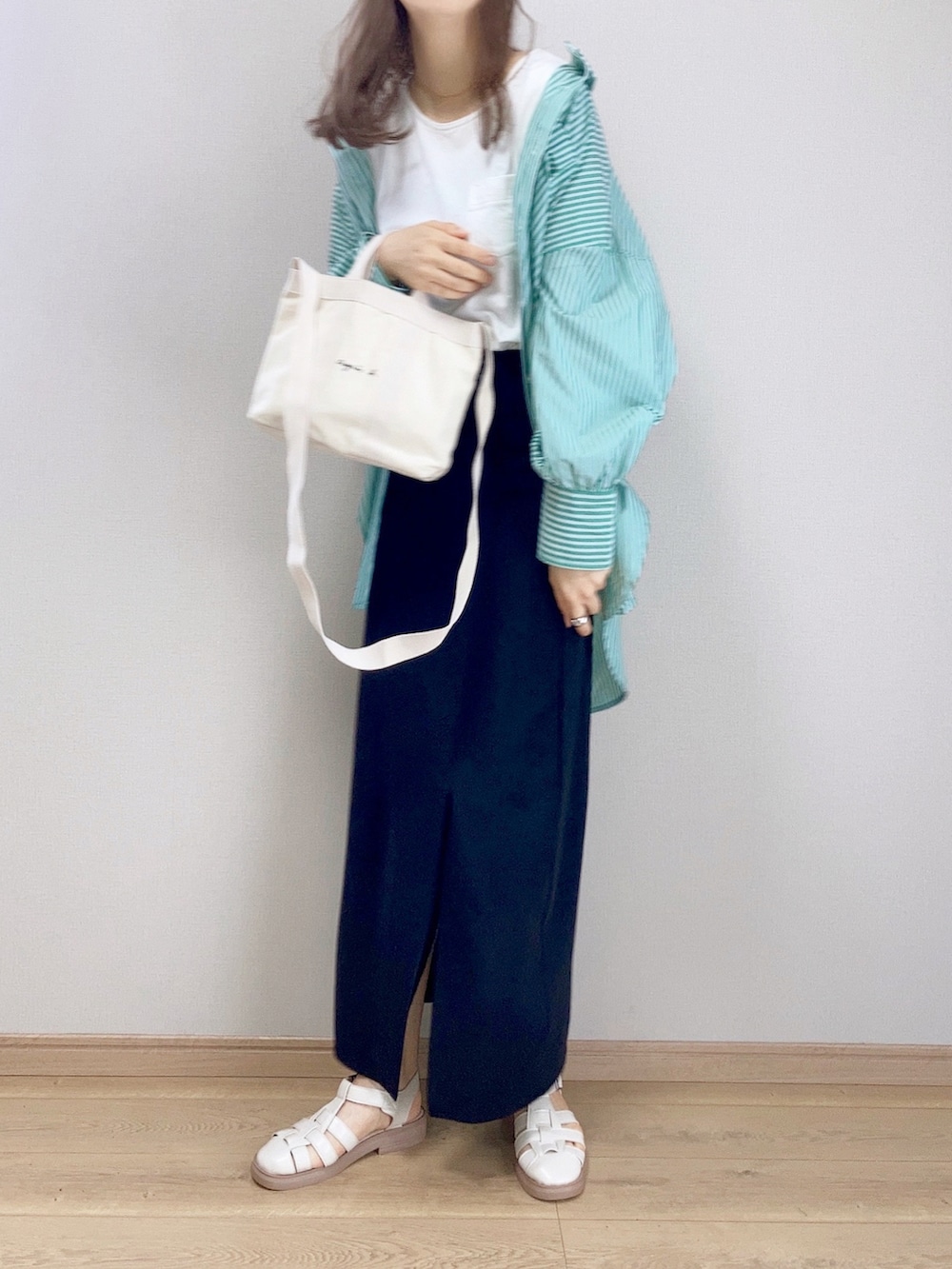 ホワイト系のトートバッグ、グリーン系のシャツ/ブラウス、ブラック系のスカートを着用したレディースの春コーディネートの2枚目の写真