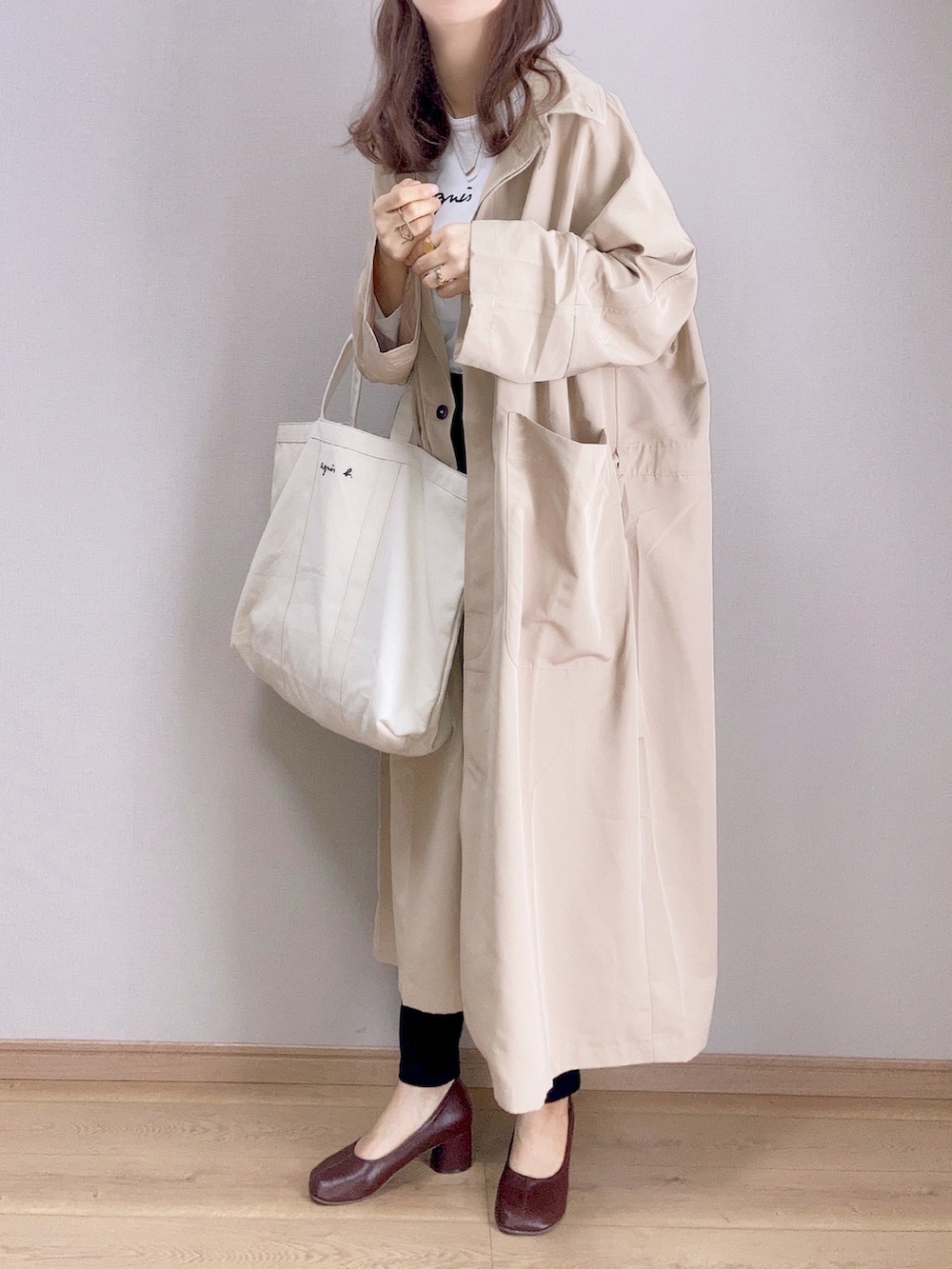 ベージュ系のトレンチコート、ホワイト系のTシャツ/カットソー、ブラック系のデニムパンツを着用したレディースの春コーディネートの2枚目の写真