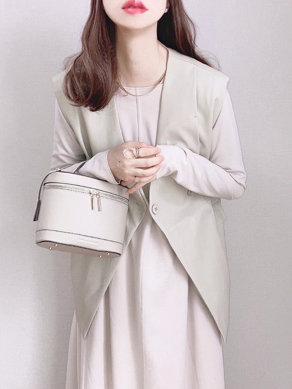 ベージュ系のベスト、ベージュ系のワンピース、ベージュ系のショルダーバッグを着用したレディースの春コーディネートの2枚目の写真