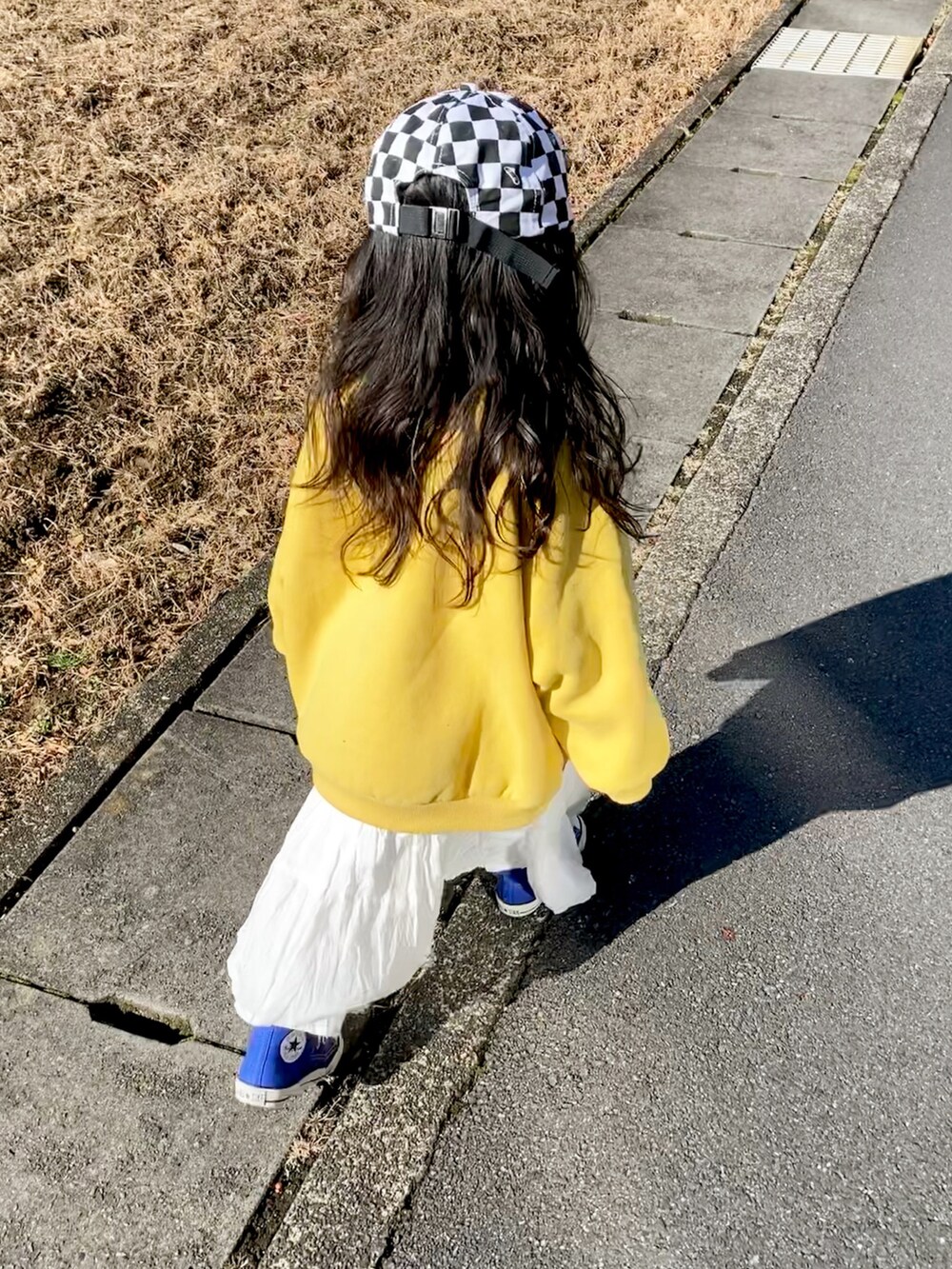 イエロー系のスウェット、ホワイト系のスカート、ブルー系のスニーカーを着用したキッズの冬コーディネートの4枚目の写真