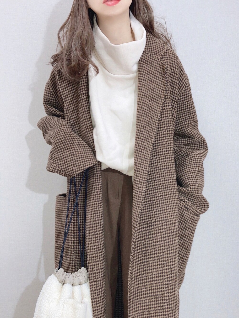 ブラウン系のチェスターコート、ホワイト系のスウェット、ブラウン系のその他パンツを着用したレディースの冬コーディネートの2枚目の写真