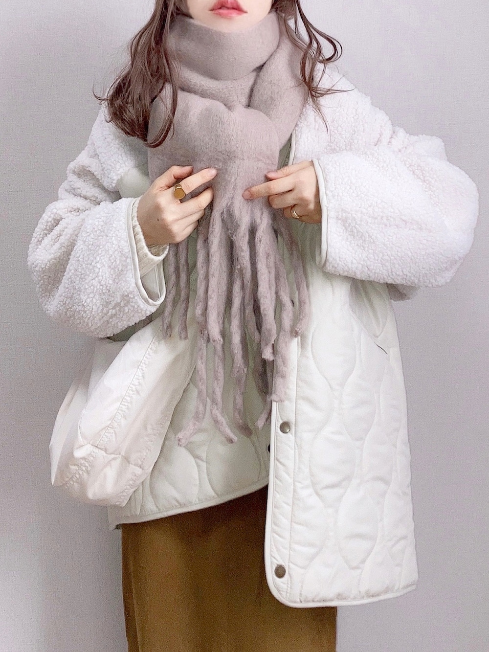 ホワイト系のブルゾン、グリーン系のニット/セーター、ブラウン系のスカートを着用したレディースの冬コーディネートの3枚目の写真