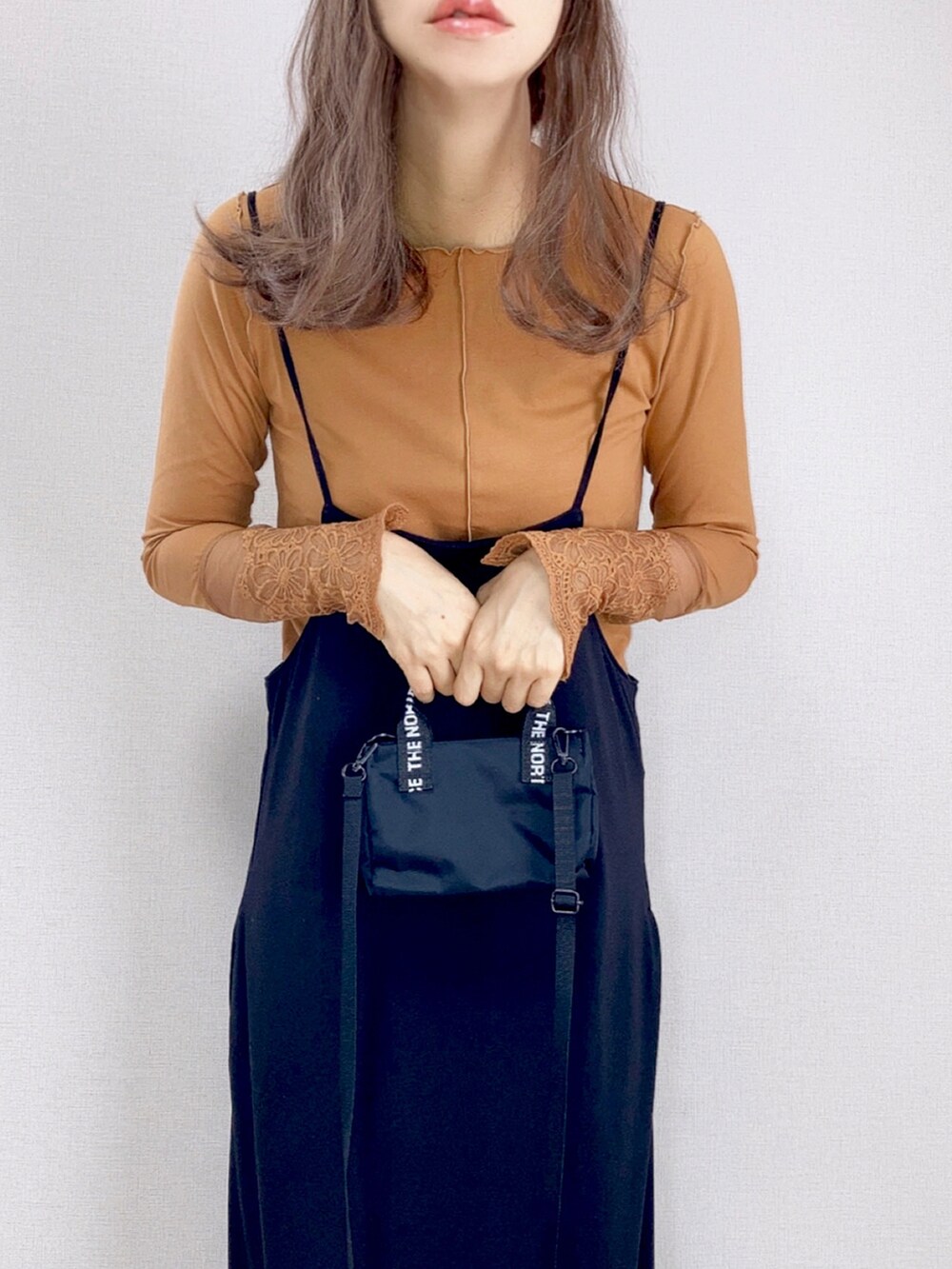 イエロー系のTシャツ/カットソー、ブラック系のワンピース、ブラック系のショルダーバッグを着用したレディースの秋コーディネートの2枚目の写真