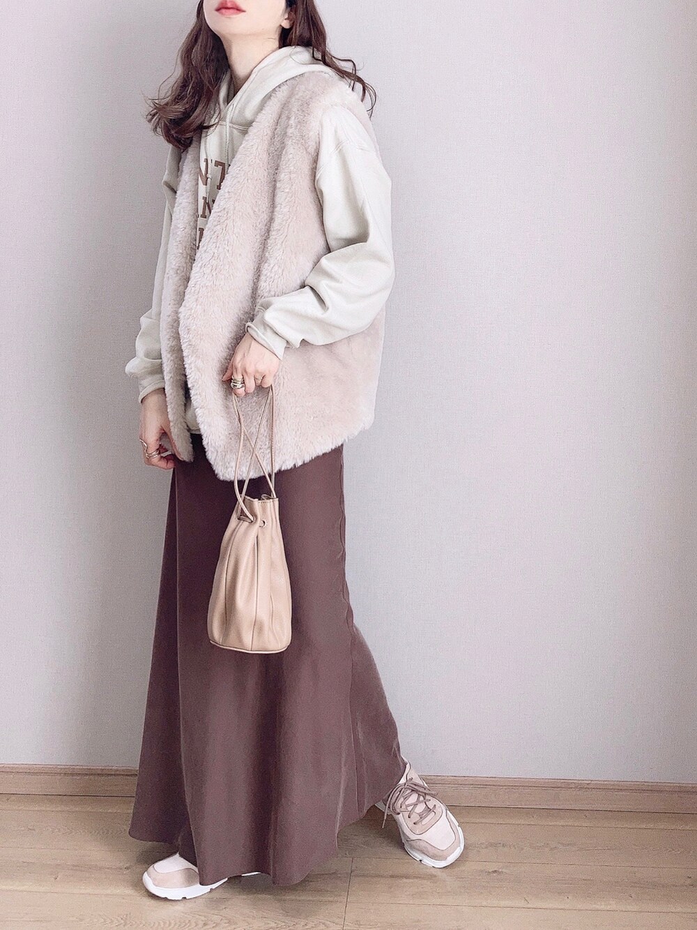 ピンク系のスニーカー、グレー系のベスト、ブラウン系のスカートを着用したレディースの冬コーディネートの2枚目の写真