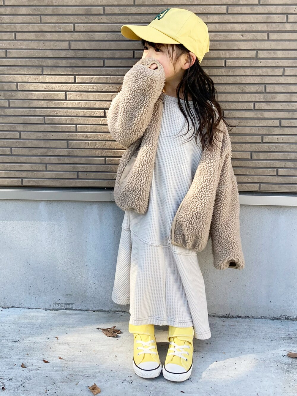 ベージュ系のワンピース、イエロー系のスニーカー、イエロー系のキャップを着用したキッズの冬コーディネートの5枚目の写真