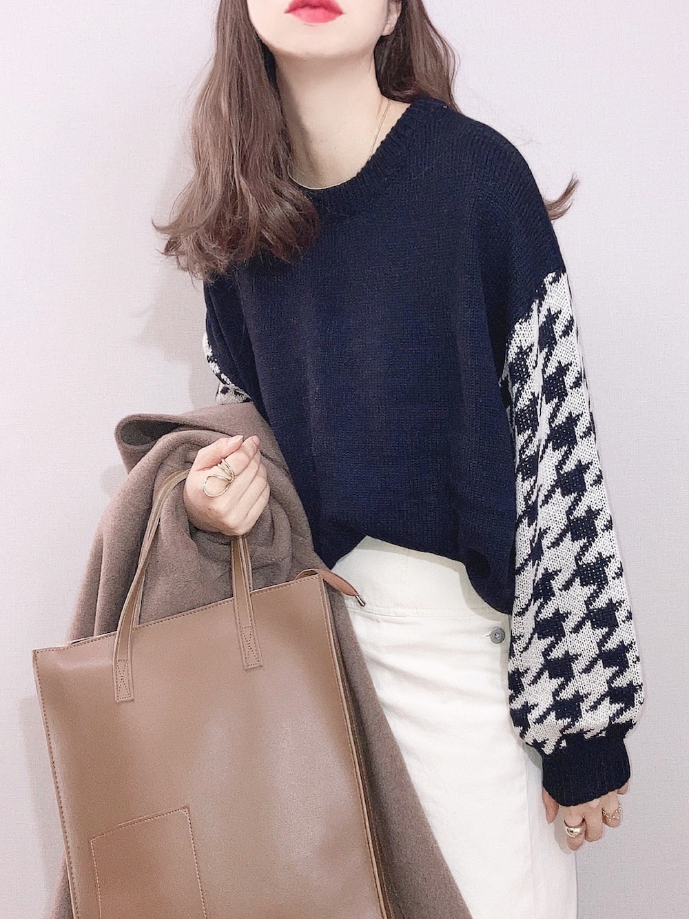 ブラック系のニット/セーター、ホワイト系のスカート、イエロー系のトートバッグを着用したレディースの冬コーディネートの2枚目の写真