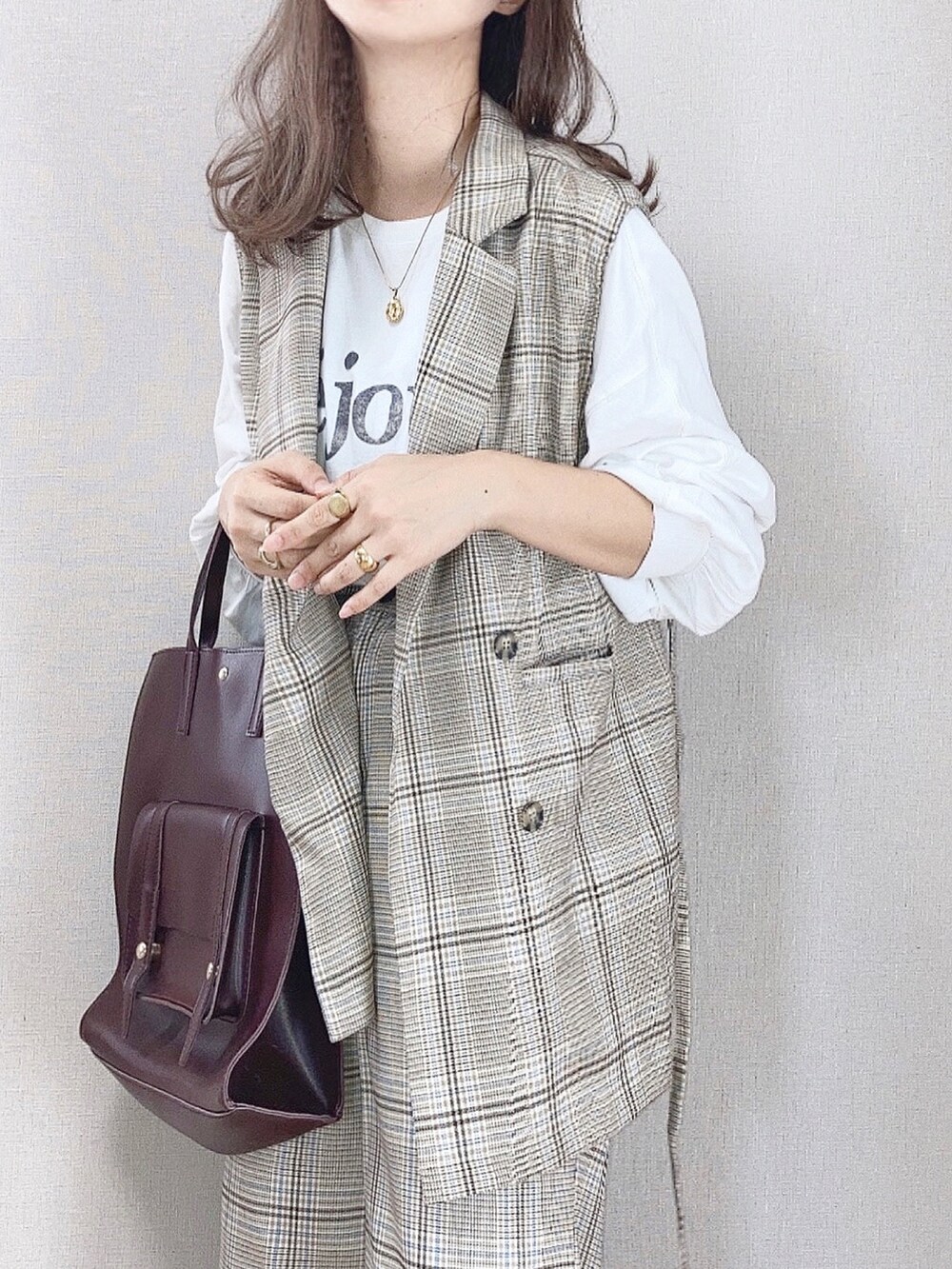 ベージュ系のベスト、ベージュ系のチノパンツ、ホワイト系のTシャツ/カットソーを着用したレディースの秋コーディネートの3枚目の写真