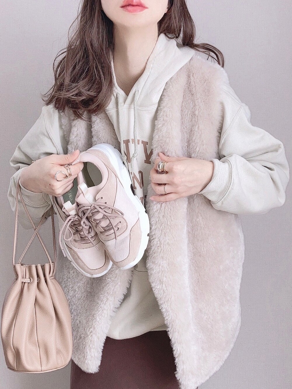 ピンク系のスニーカー、グレー系のベスト、ブラウン系のスカートを着用したレディースの冬コーディネートの3枚目の写真