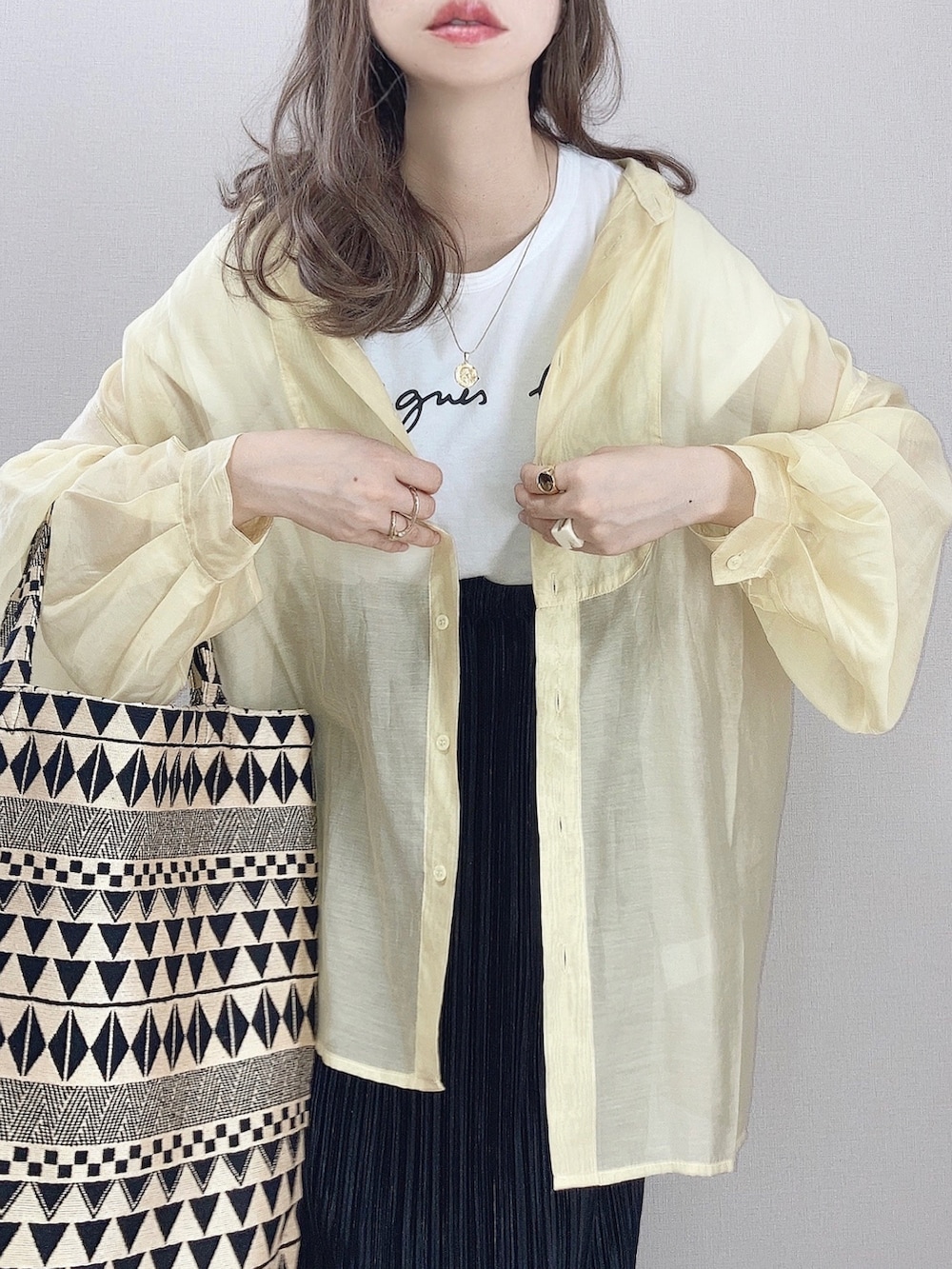 ホワイト系のTシャツ/カットソー、イエロー系のシャツ/ブラウス、ブラック系のスカートを着用したレディースの春コーディネートの2枚目の写真