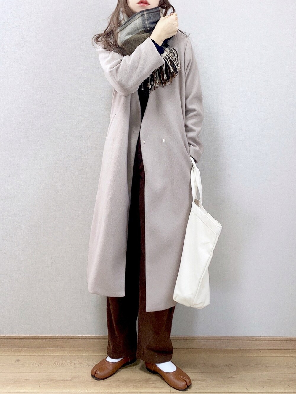 グレー系のノーカラーコート、ホワイト系のトートバッグ、ブラウン系のその他パンツを着用したレディースの冬コーディネートの3枚目の写真