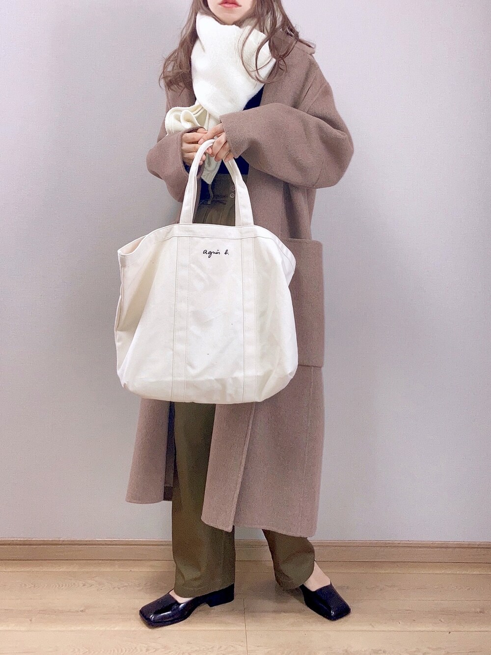ブラウン系のチェスターコート、グリーン系のチノパンツ、ホワイト系のトートバッグを着用したレディースの冬コーディネートの2枚目の写真