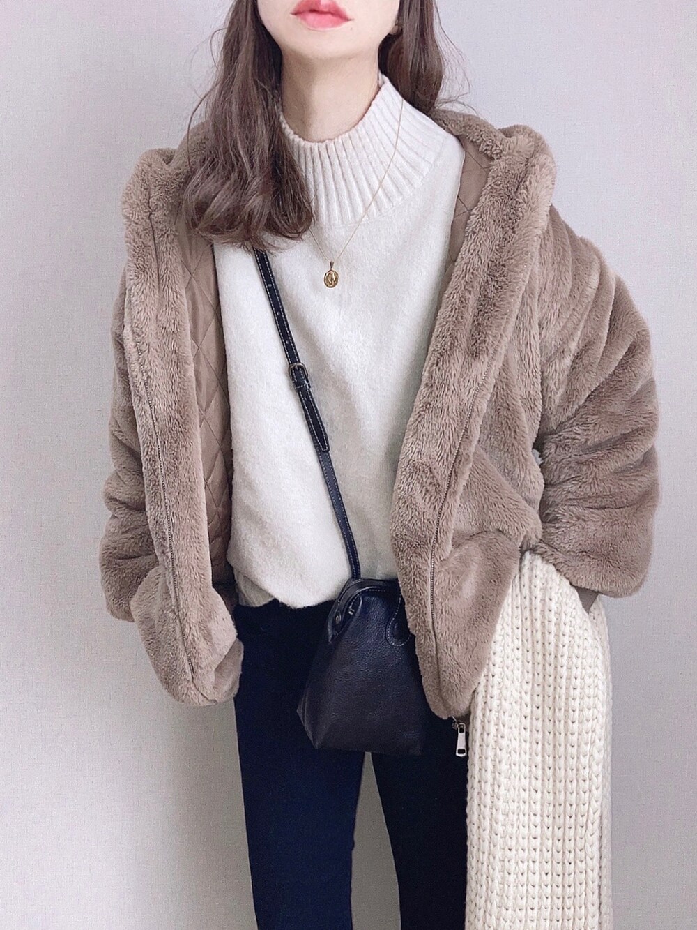 ブラウン系のブルゾン、ホワイト系のニット/セーター、ブラック系のデニムパンツを着用したレディースの冬コーディネートの2枚目の写真