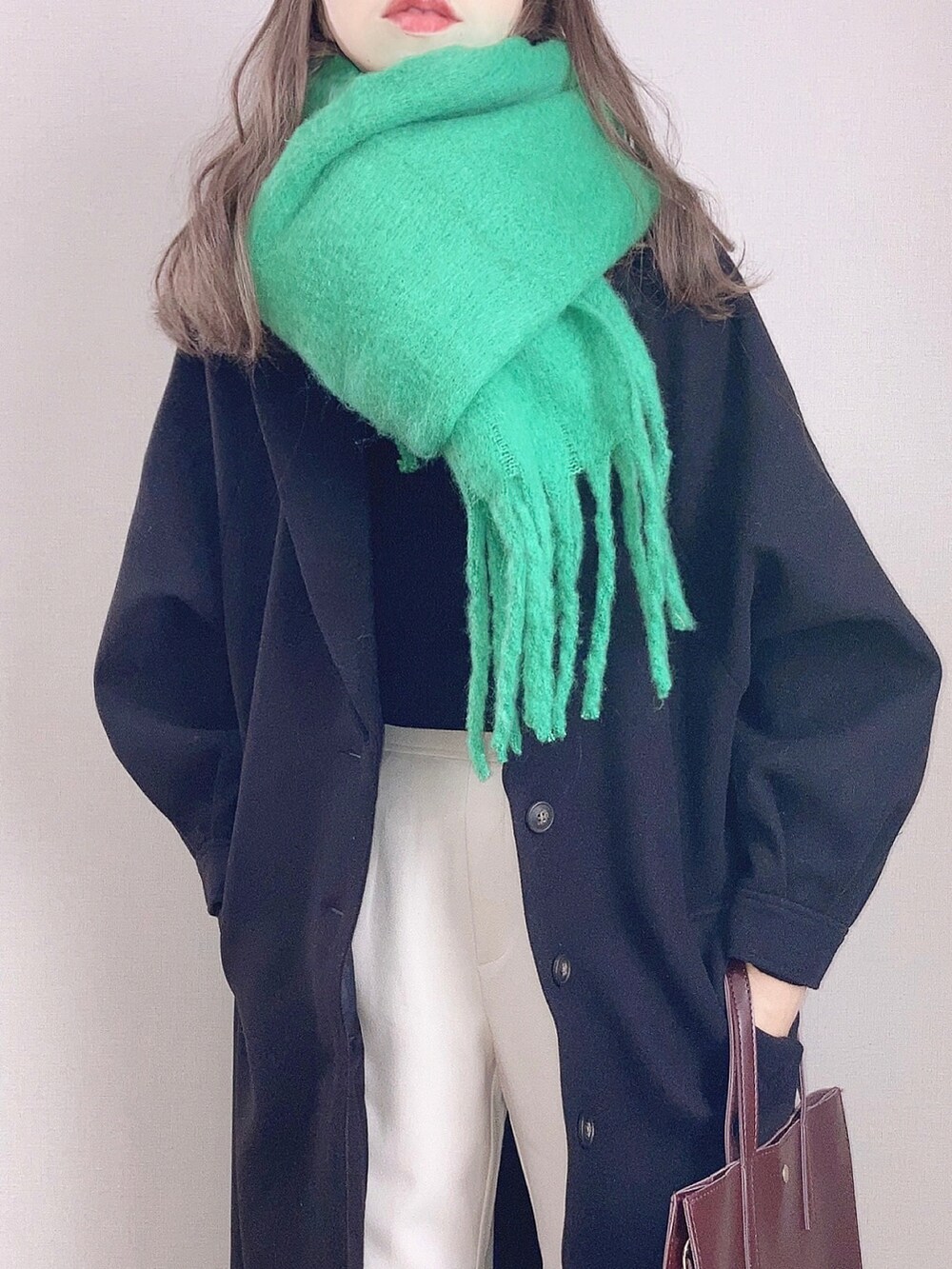 ブラック系のチェスターコート、ホワイト系のその他パンツ、ブラウン系のハンドバッグを着用したレディースの秋コーディネートの2枚目の写真