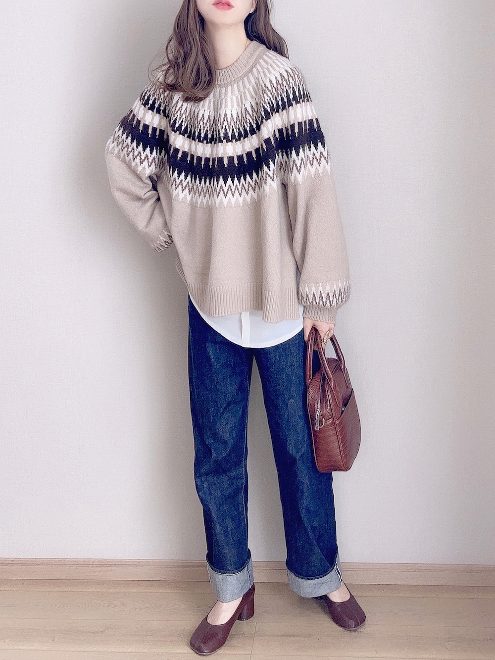 ベージュ系のニット/セーター、ブルー系のデニムパンツ、ブラウン系のハンドバッグを着用したレディースの秋コーディネートの3枚目の写真