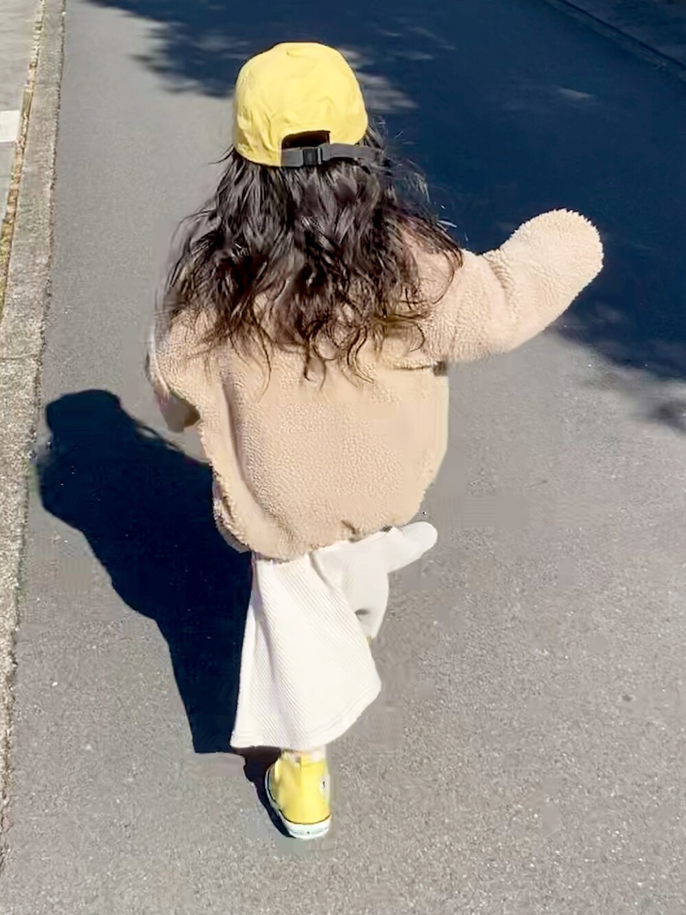 ベージュ系のワンピース、イエロー系のスニーカー、イエロー系のキャップを着用したキッズの冬コーディネートの2枚目の写真