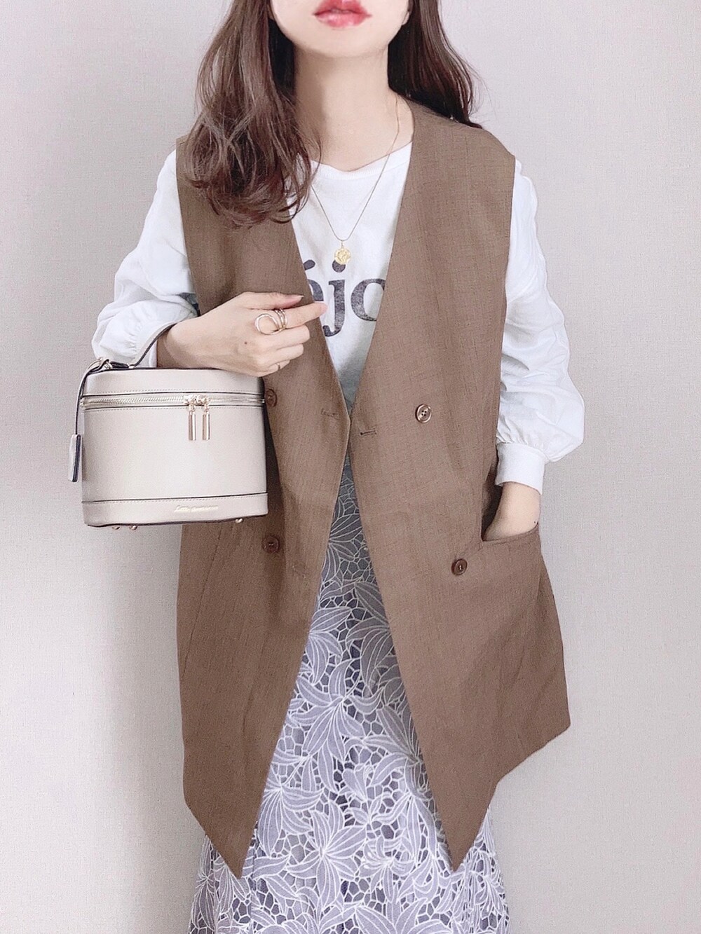 ブルー系のスカート、ホワイト系のスニーカー、ブラウン系のベストを着用したレディースの春コーディネートの2枚目の写真