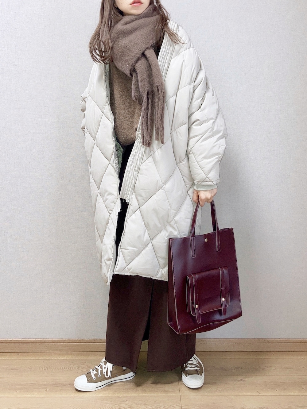 ホワイト系のダウンジャケット/コート、ブラウン系のスカート、ブラウン系のハンドバッグを着用したレディースの冬コーディネートの2枚目の写真