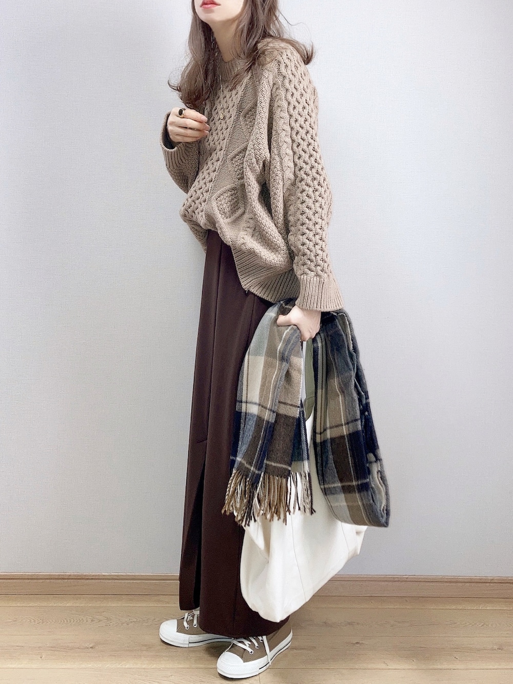 ベージュ系のニット/セーター、ブラウン系のスカート、ホワイト系のトートバッグを着用したレディースの冬コーディネートの2枚目の写真